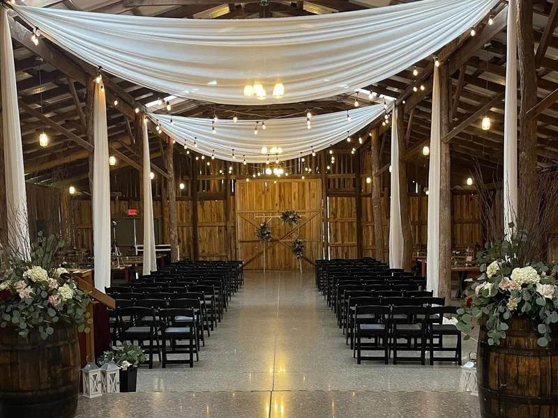 The main hall set for an indoor ceremony with ceiling drapery and rows of black chairs