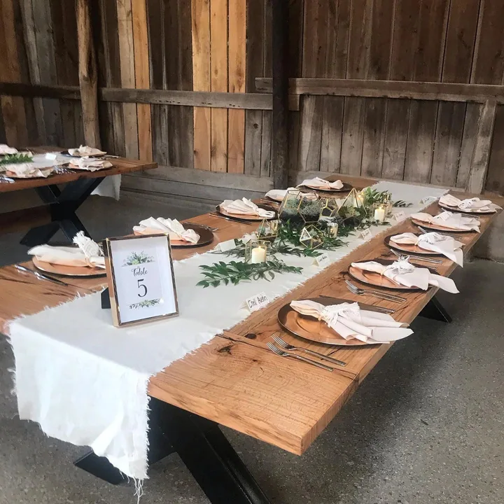 A long oak slab table set for a reception in the barn
