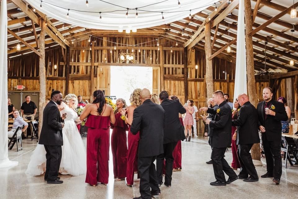 A wedding party dancing on the polished floor inside the barn