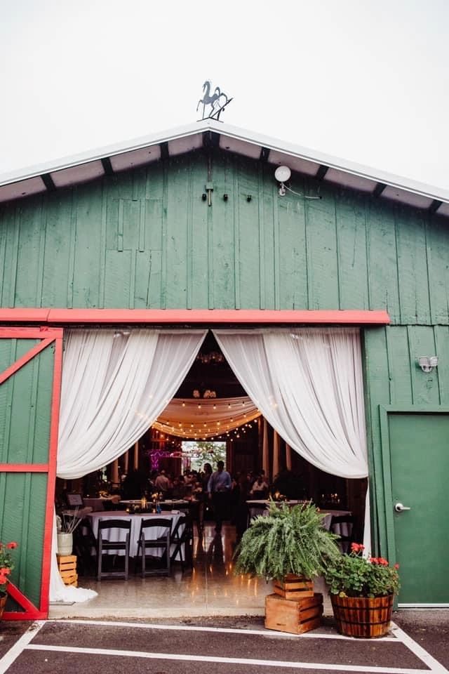 The open green barn doors with white drapery and a reception set inside