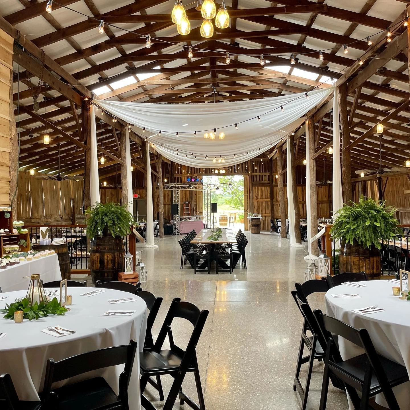 The main hall set for a reception with round tables under ivory drapery
